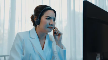 Fotobehang Businesswoman wearing headset working in office to support remote customer or colleague. Frustrated and tired call center customer support agent facing problem on providing vivancy service © Summit Art Creations