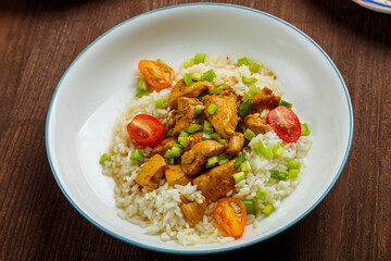 Thai chicken with rice in sauce on a plate on a wooden table