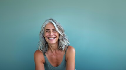 A woman of fifty years old smiles close-up on a blue background. Happy old age, healthy teeth.