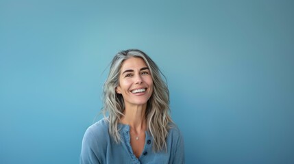 A woman of fifty years old smiles close-up on a blue background. Happy old age, healthy teeth.