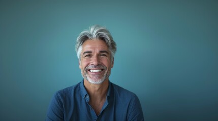 A middle-aged man with gray hair on a blue background with a pleasant smile. Health and beauty, healthy teeth. - obrazy, fototapety, plakaty
