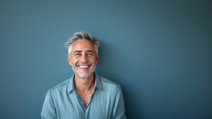 A middle-aged man with gray hair on a blue background with a pleasant smile. Health and beauty, healthy teeth. - obrazy, fototapety, plakaty
