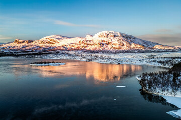 Aerial view of mountains and their reflection in the lake at sunrise in Swedish Lapland with bright...