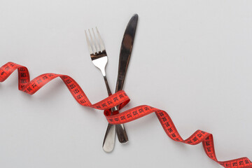 Measuring tape with fork and knife on color background, top, view.Weight loss concept