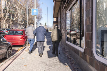 A group of older people walking on a sidewalk in the city