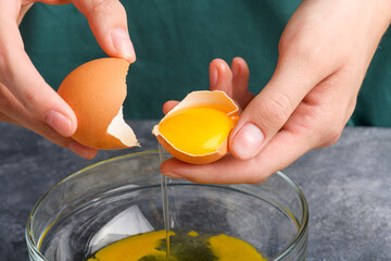 Hands holding the eggshells with yolk, close up. Housewife hands separete yolk and white into a glass bowl, the process of cooking, close up