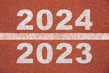 Happy new year 2024 symbolizes the start of the new year. Rear view of a man preparing to run on the athletics track engraved with the year 2024. The goal of Success. Getting ready for the new year.