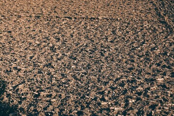 Freshly plowed field ready for seeding and planting in spring. Farmland. Empty plowed farm land prepared for the new crop. Agriculture. Brown black soil near village