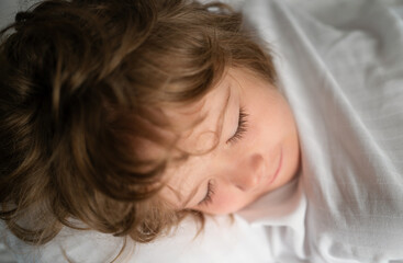Kids sleeping alone in comfortable bed with white linens.