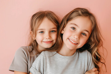 Two 10-year-old girls of European appearance in gray T-shirts smile sweetly on a pink background, minimalism. Brothers and sisters, twins concept