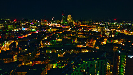 Nighttime cityscape with illuminated buildings and streets, showcasing urban architecture and...