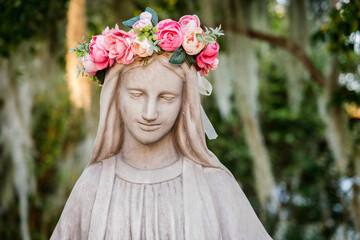 Virgin Mary statue with a crown of flowers outside