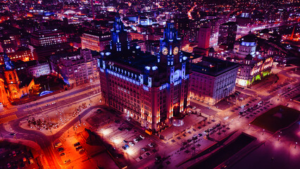 Aerial night view of an illuminated historic building in an urban cityscape in Liverpool, UK.