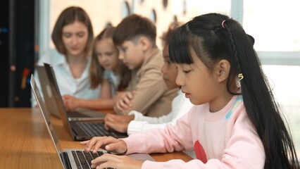 Smart asian girl working on laptop and turn head to doing ok or okay at camera. Diverse children...