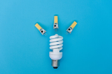 Energy saving light bulb and little 12V led bulbs spaced on a blue background. Idea concepts. Advertising or presentation purposes