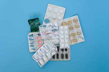 Group of different pills and tablets plastic blisters spaced on a blue background. Pharmaceutical medication. Healthcare and medicine concept. Advertising or presentation purposes