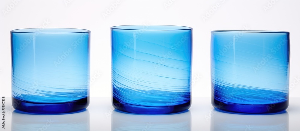 Poster three azure glasses containing liquid are arranged in a row on a white surface, creating a beautiful