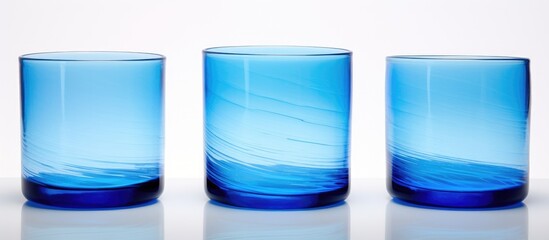 Three azure glasses containing liquid are arranged in a row on a white surface, creating a beautiful display of tints and shades of blue