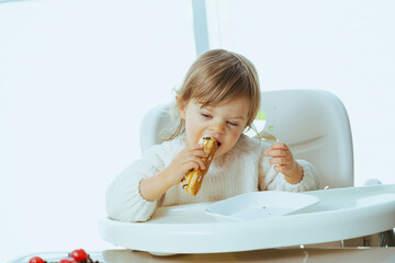 Cute toddler eats eclair with chocolate, harm from sugar to the health of a child, tooth problems,...