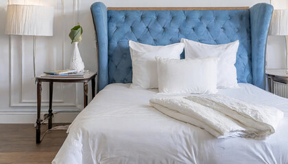 interior with white bed linen on the sofa bedroom with bed white bedding and bedside table white pillows duvet and duvet case on bed with blue headboard front view