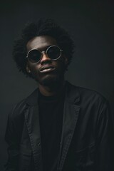 Stylish man wearing sunglasses and a black shirt. Suitable for fashion or lifestyle themes.