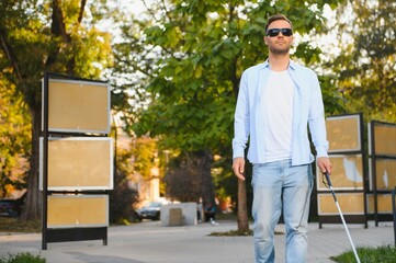 Blind Man Walking On Sidewalk Holding Stick.