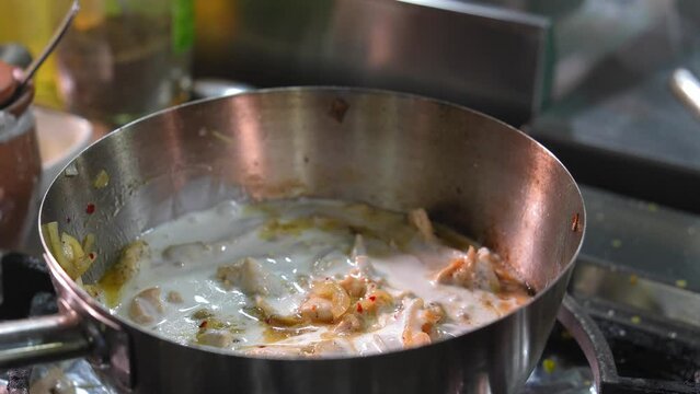 Chef handmade sauce with mushrooms sliced in pan in kitchen of restaurant Frying pan with fried mushrooms with onions in bechamel sauce. Chef's hand adds milk