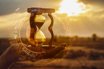 Double exposure of hand with hourglass and sunset in city.