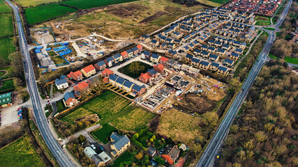 Aerial view of suburban housing development with construction site, roads, and green fields in Harrogate, North Yorkshire.
