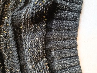 The process of knitting a jumper made of black and gray wool with sequins. High quality photo