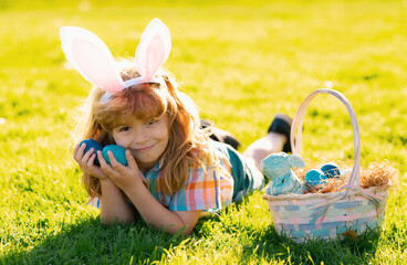 Kids in bunny ears on Easter egg hunt in garden. Children with colorful eggs in grass.