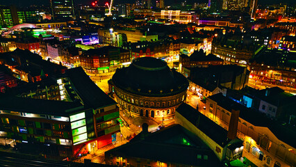 Nighttime cityscape with illuminated buildings and construction cranes, showcasing urban development in Leeds, UK.