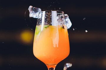 ice cubes falling into a splashing orange cocktail.