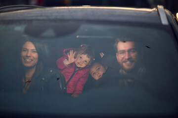 In the nighttime hours, a happy family enjoys playful moments together inside a car as they journey...