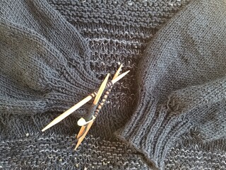 The process of knitting a jumper made of black and gray wool with sequins. High quality photo