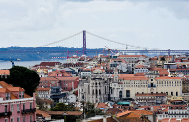 Fototapeta na wymiar Panoramic view of the cityscape of Lisbon, Portugal, with Sao Jorge Castle and the red roofes of the Alfama district until the Tagus river on a sunny day. Blue sky. April 25 Bridge