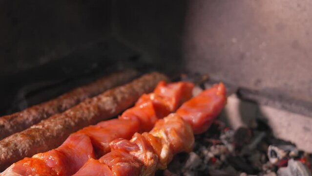 Close-up of an appetizing kebab or shashlik made of fresh meat and lula kebab is cooked on a charcoal grill with smoke. Vertical photo