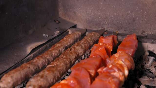Close-up of an appetizing kebab or shashlik made of fresh meat and lula kebab is cooked on a charcoal grill with smoke. Vertical photo