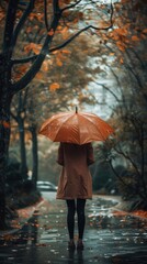 Young woman in raincoat with orange umbrella in the autumn park.