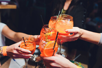 women raising a glasses of aperol spritz at the dinner table.