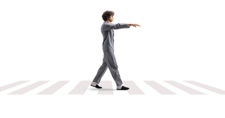 Full length profile shot of a guy in pajamas sleepwalking on a street