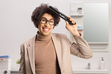 Guy with curly hair using a hair straightener at home