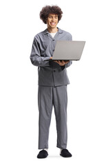 Young man in pajamas standing and using a laptop computer