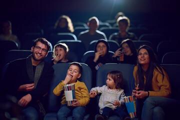A modern family enjoys quality time together at the cinema, indulging in popcorn while watching a...