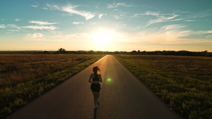 silhouette sports girl running along road sunset, runner athlete's leg, preparing races, athletic...