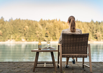 Young happy woman drinking wine enjoying beautiful forest lake view from home on summer day 