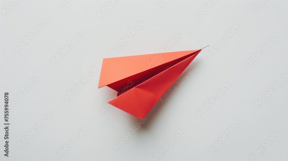 Poster A red paper airplane on a white surface, suitable for various concepts.