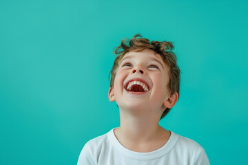 Laughing Child in White Shirt on Bright Turquoise Background with Copy Space