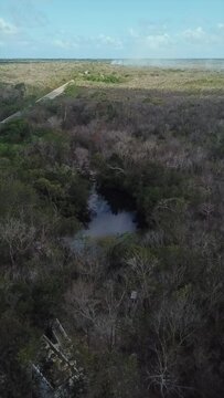 Vertical aerial view time-lapse  of cenote Carwash (Aktun Ha) as a cloud passes in top of it  until the sun reveals the clarity of the water, Tulum, Riviera Maya, Mexican Caribbean, Mexico