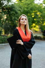 Beautiful university graduate in a black gown. The happy student successfully completed university...